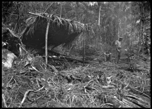 A shelter in the bush and timber workers boiling a billy nearby, Piha