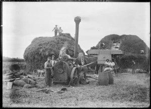 Farm workers, steam powered threshing machine and haystacks