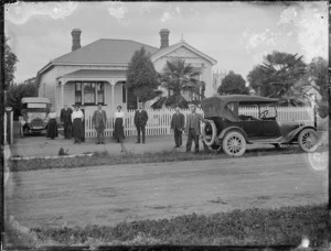 Group and cars outside a house, Hastings