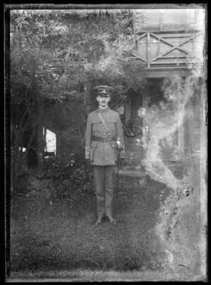 Solider in dress uniform wearing ceremonial sword and peaked cap