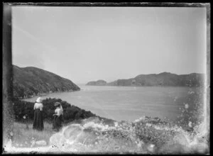 Two women standing on a hillside at a harbour entrance