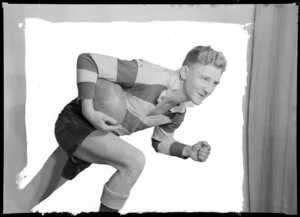 Rugby player posing with ball in studio