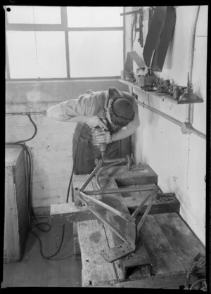 Factory worker drilling metal frame