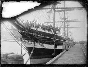 View of the prow of the sailing ship Waimate, with the crew on board looking towards the camera. At Port Chalmers.