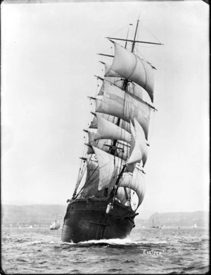 Sailing ship 'Eliezer' under full sail, with small yachts and hills in background.