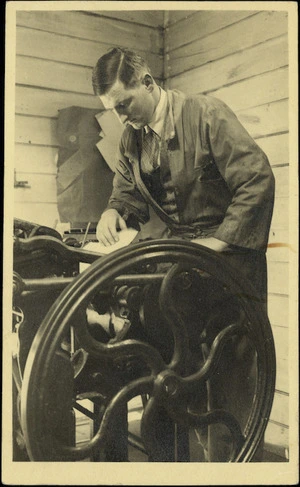 Glover, Denis : Photograph of Denis Glover operating a platen press