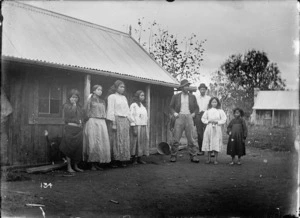Maori family group in front of a wooden building