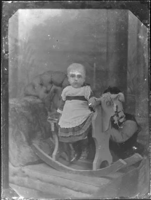 Unidentified infant on rocking horse