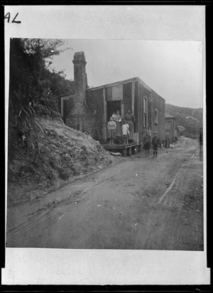 Group of women and children outside the house of coal miner Thomas Donaldson, Denniston Hill, West Coast - Photograph taken by John Pascoe