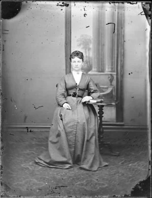 Unidentified woman seated, wearing dress with V neck line, tight above the hips