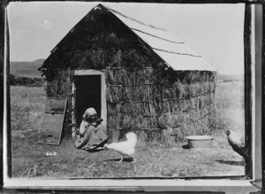 Old Maori woman sitting at the entrance of her whare