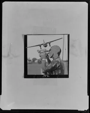 Photomontage of man with head of The Phantom operating film camera, plane overhead