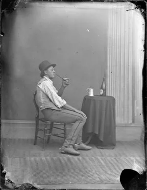 Unidentified Maori man with a pipe, tankard and bottle of beer
