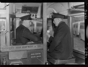 Two unidentified men in uniform sitting in a bus at Bus Drivers' School