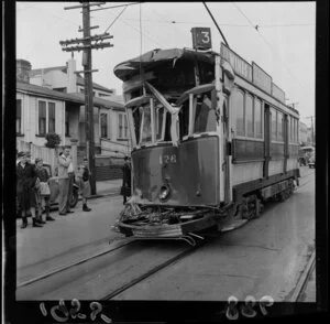 Tram accident (tram 176, route 3), Kent Terrace, Wellington, including an unidentified man and schoolboys looking on, as well as a sign for Glenvale Wines and Liquers on the side of the tram