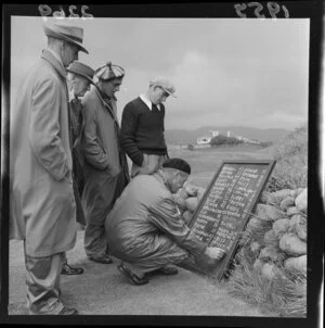 Men with various hats examining a scoreboard at the Caltex Gold Tournament