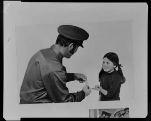 Service station attendant putting plaster on little girl's finger