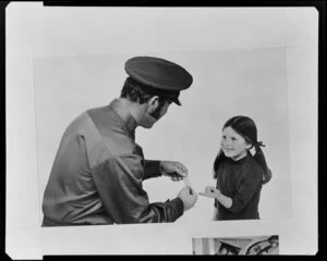 Service station attendant putting plaster on little girl's finger