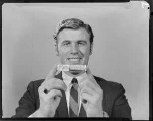 Portrait of man in suit holding packet of Sparkles lollies