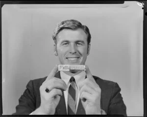 Portrait of man in suit holding packet of Sparkles lollies