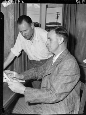 Jim Barnes and Bill Holley looking at paperwork, 1950 British Empire Games village, Ardmore