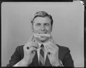 Portrait of man in suit holding packet of Sparkles lollies