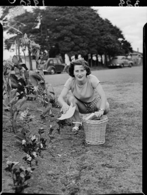 Unidentified woman beside flower garden, Auckland