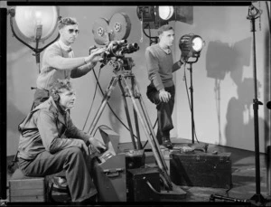 Cameraman, sound operator, and lighting technician working in a film studio