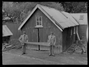 Ralph (left) and Hugh Beetham holding a long pitsaw that was used in the building of the whare behind them at Brancepeth Station