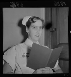 Miss G Rhind, in a nurse's uniform and holding up an open book