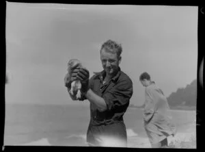 A man holding a penguin found at Scorching Bay, Karaka Road, Wellington