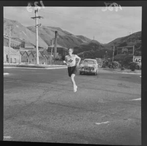 Unidentified torch bearer, running in the Southland Centennial torch relay from Waitangi to Invercargill, at intersection of Ngauranga Gorge and Hutt Road