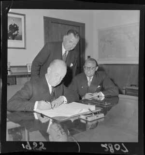 Minister signing Social Security Agreement, Sidney Holland (Prime Minister) standing