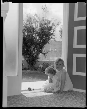 Phillipa Tait with doll, at front door of Tait house