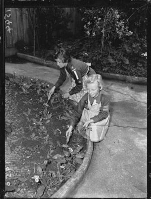 Girl Guide, and a Brownie, working in a garden during Bob a Job Week