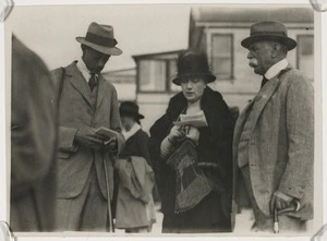 Two men and a woman study the race book