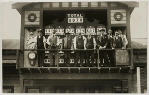 Men standing in front of a tote board