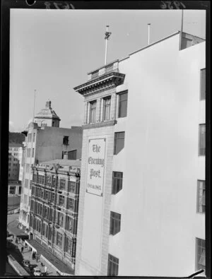 View of the Evening Post building with a man fixing the flag pole on top; Cooper Buildings is next door, Wellington