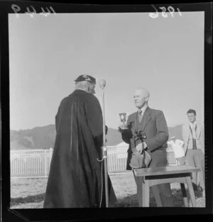 Unidentified man handing over a trophy cup to a woman at the Races, Trentham, Upper Hutt
