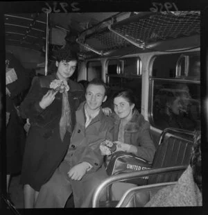 Three Hungarian refugees, two young women with bunches of flowers and a young man, in a bus, Wellington