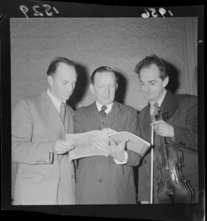 National Orchestra leaders, including concert master/ 1st violinist Vincent Aspey (far right), conductor James Robertson [centre?], and an unidentified man, looking over a Debussy score