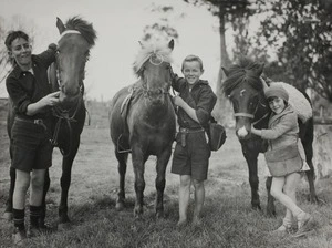 Three schoolchildren posing with their horses