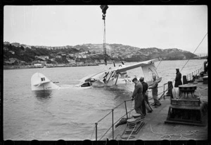 Men on floating crane beside partly submerged Royal New Zealand Air Force Catalina flying boat, Evans Bay, Wellington