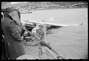 Men on floating crane watching a Royal New Zealand Air Force Catalina flying boat being raised from sea, Evans Bay, Wellington