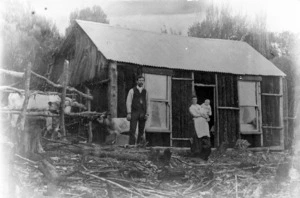 Man, woman and baby outside a hut, Heathfield settlement