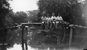 Rewi Alley and three boys sitting on a bridge