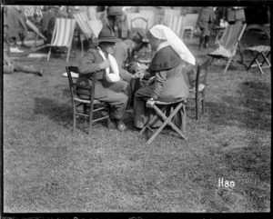 A wounded World War I soldier talking to a nurse at the garden party in the grounds of the New Zealand Stationary Hospital