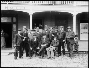 Group of men posing in front of a hotel