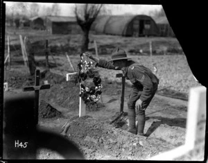 New Zealand soldier stands over the grave of a fallen comrade