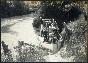 Two men and children in a boat on the Mokau River
